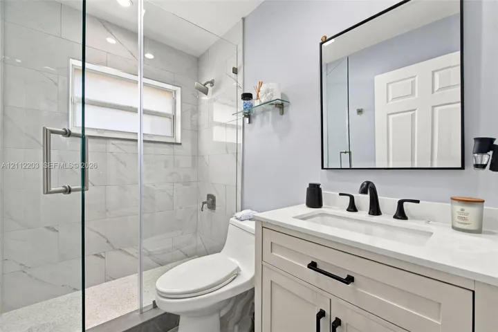 Bathroom featuring a vanity with light-colored cabinetry, a stone-composite countertop, and a rectangular undermount sink with matte black hardware