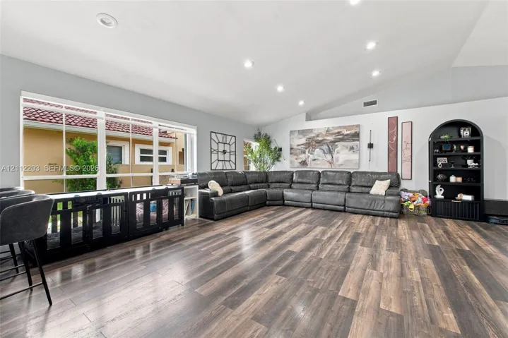 Spacious interior featuring a vaulted ceiling, wood-finish flooring, recessed lighting, and a large multi-pane window