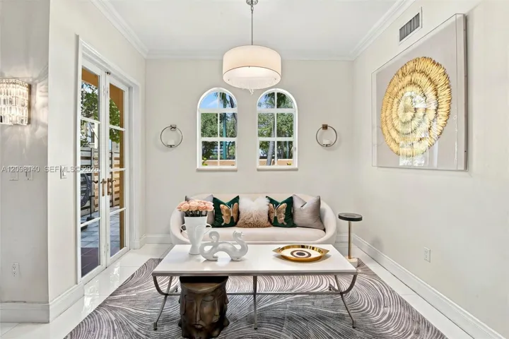 Arched windows with grid panes, glass-paned double doors, crown molding, and a central drum pendant light fixture
