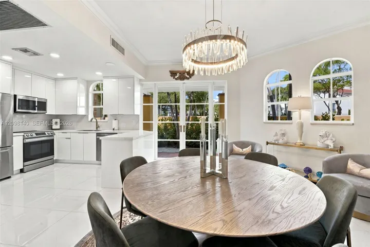 Kitchen and dining area featuring high-gloss cabinetry, stainless steel appliances, polished stone-finish flooring, a contemporary drum chandelier, and arched windows