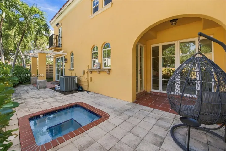 Stucco exterior featuring an arched loggia, in-ground plunge pool with brick coping, paved patio, and a pergola-covered walkway