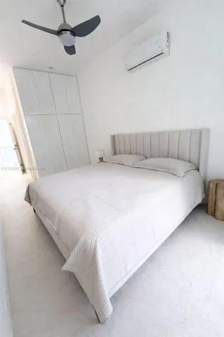 Built-in floor-to-ceiling cabinetry, wall-mounted ductless air conditioning unit, ceiling fan with integrated lighting, and neutral-toned flooring