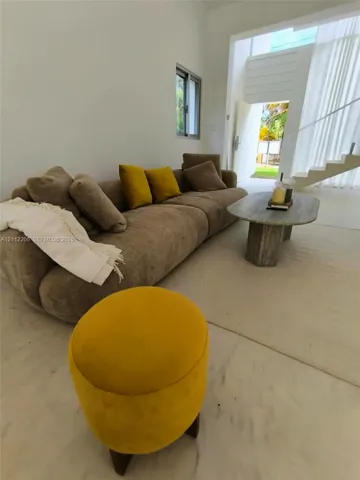 Interior space featuring white stone flooring, high ceilings, a sculptural staircase with a metal handrail, and large window placement