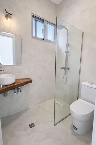 Walk-in shower featuring a frameless glass partition, wall-mounted rain shower head, live-edge wood floating vanity, rounded vessel sink, and textured wall finish