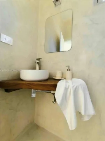 Wall-mounted natural wood vanity featuring a circular vessel sink, polished metal faucet, and mounted square mirror