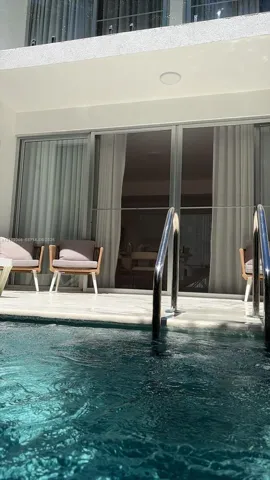 Swimming pool featuring stone-finish decking, recessed exterior lighting, and floor-to-ceiling sliding glass doors with metal frames
