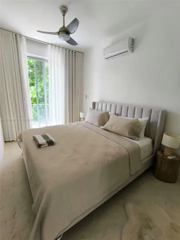 Floor-to-ceiling glass door with full-length drapery, wall-mounted ductless air conditioning unit, and ceiling fan with integrated lighting