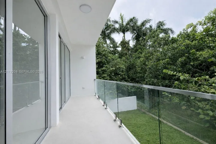Covered balcony featuring a frameless glass railing, flush-mount ceiling lighting, and large sliding glass doors