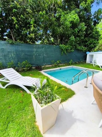 In-ground swimming pool with metal ladder, concrete patio, and manicured lawn