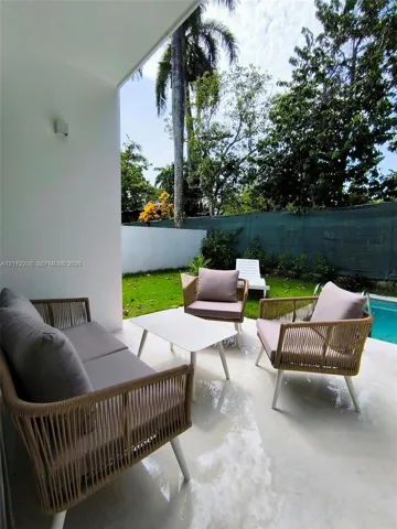 Covered patio featuring smooth concrete flooring, manicured lawn, perimeter fencing, and swimming pool