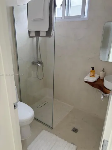Walk-in shower featuring a glass enclosure, floor-to-ceiling textured wall finishes, live-edge wood floating vanity, round vessel sink, and chrome fixtures