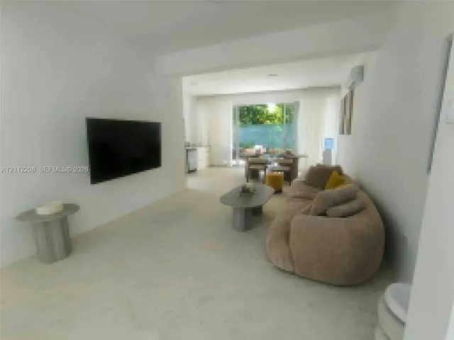 Open-concept interior featuring neutral polished flooring, smooth white walls, recessed ceiling lighting, and sliding glass doors