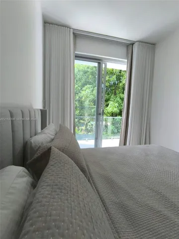 Floor-to-ceiling drapery, glass-paneled sliding door, and glass-railed exterior balcony