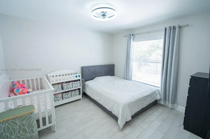 Neutral-toned interior featuring wood-finish tile flooring, a recessed ceiling fan light fixture, and horizontal window blinds
