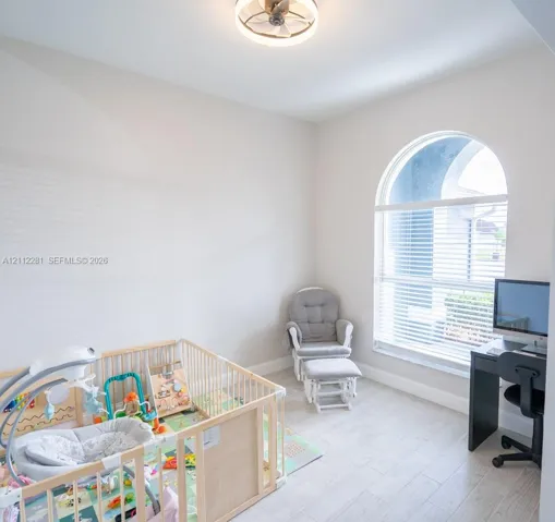Arched window with light-toned wood-finish flooring and integrated circular ceiling fan fixture