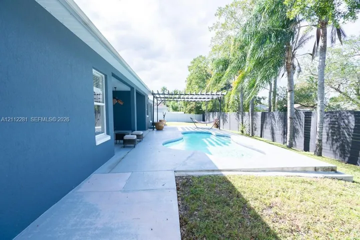 Private backyard featuring a swimming pool, concrete patio, wooden pergola, and perimeter​​‌​​​​‌​​‌‌​‌‌​​​‌‌​‌​‌​‌​​​‌​​ fencing