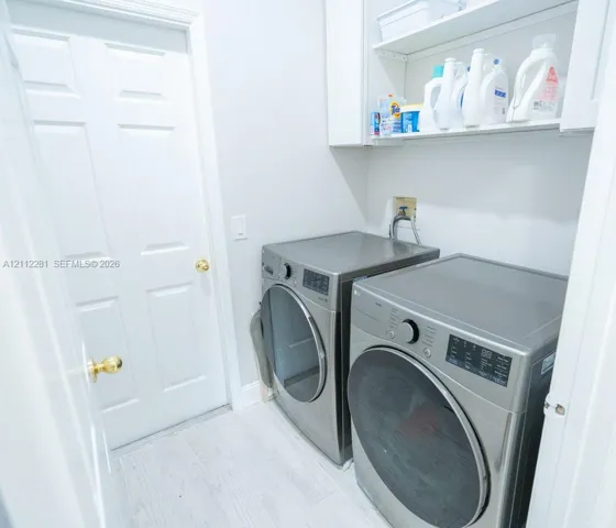 Dedicated utility space featuring white built-in cabinetry, upper shelving, and white tile flooring