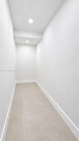 Neutral-toned ceramic floor tiling paired with minimalist white walls and recessed ceiling lighting
