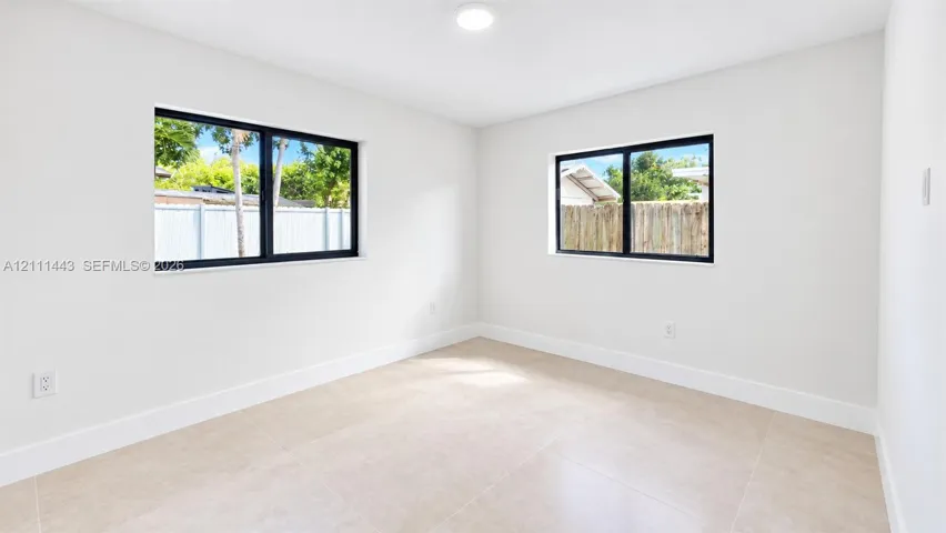 Neutral-toned oversized tile flooring, dual-aspect windows with black frames, and recessed lighting