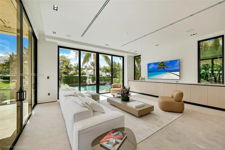 Living area featuring floor-to-ceiling glass sliding doors, recessed lighting, built-in light-tone cabinetry, and natural stone flooring