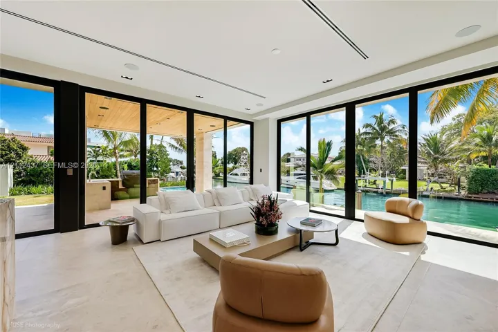 Floor-to-ceiling multi-panel glass doors, stone tile flooring, recessed ceiling lighting, and covered outdoor terrace with wood-plank ceiling