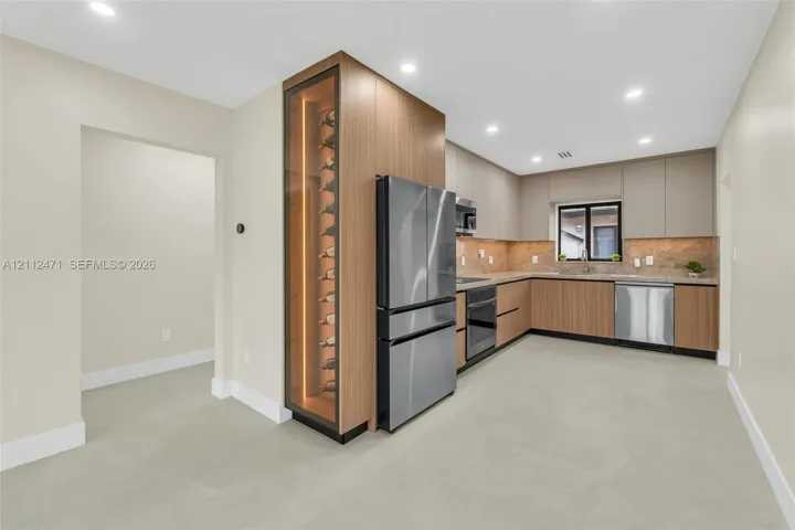 Kitchen featuring wood-finish cabinetry, stainless steel appliances, built-in temperature-controlled wine storage, stone tile backsplash, and recessed lighting