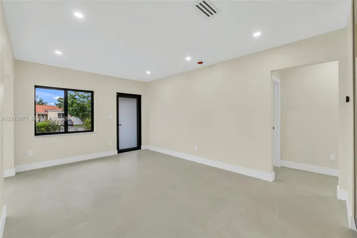 Open-concept room featuring neutral paint, large-format tile flooring, recessed ceiling lighting, and a door with frosted glass paneling