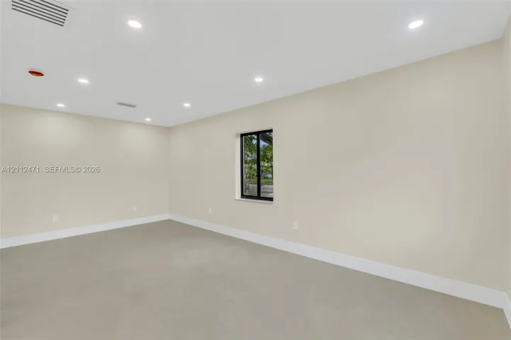 Interior space featuring neutral wall paint, smooth concrete flooring, recessed lighting, and a single window with a black frame