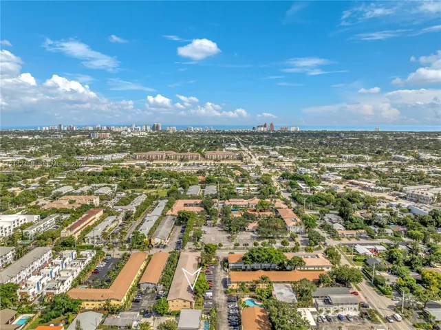 Aerial view of a multi-story residential building complex featuring pitched roofing, paved surface parking areas, and mature landscaping