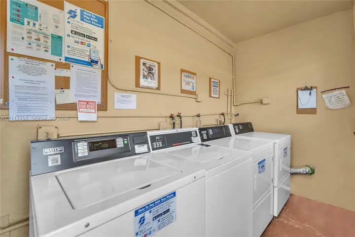 Laundry area featuring multiple top-loading washing machines and side-by-side dryers