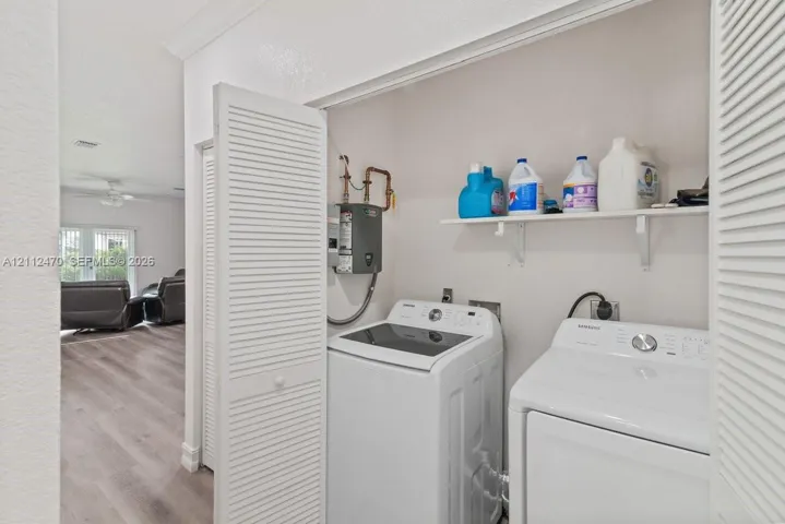 Laundry area featuring louvered bi-fold doors, wood-finish flooring, and a wall-mounted shelving unit