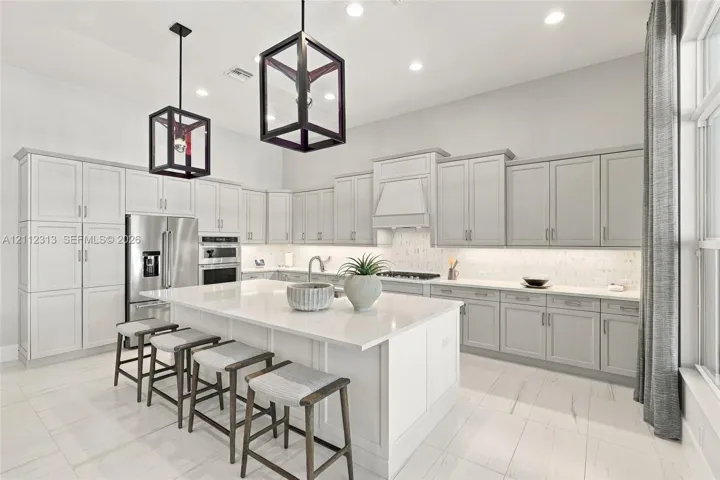 Kitchen featuring shaker-style cabinetry, quartz countertops, a central island, recessed lighting, and geometric pendant fixtures