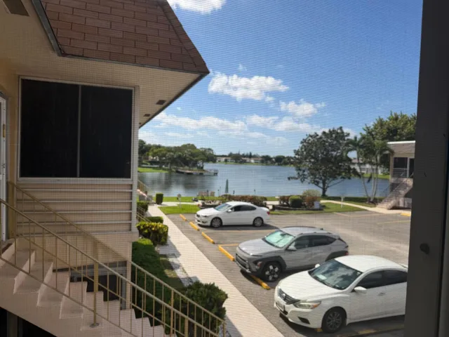 Exterior building elevation featuring metal railings, shingled roofing, and a waterfront setting