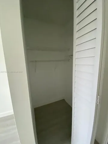 Closet featuring louvered bi-fold doors, wood-finish flooring, and built-in shelving