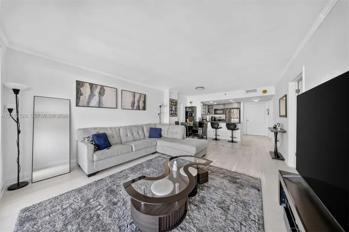Open-concept living space featuring wood-finish flooring, recessed lighting, and a kitchen equipped with a breakfast bar, stone-surface countertops, and stainless steel appliances