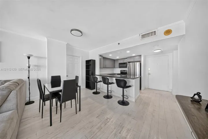 Kitchen area featuring a breakfast bar, stainless steel appliances, neutral cabinetry, light-toned wood-finish flooring, and recessed ceiling lighting