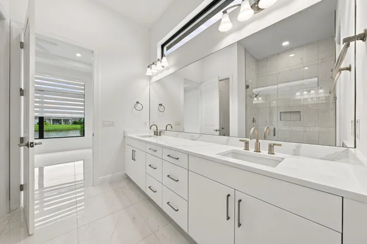 Primary bathroom with double sinks and vanity lights, upgraded cabinets and quartz countertops, transom window
