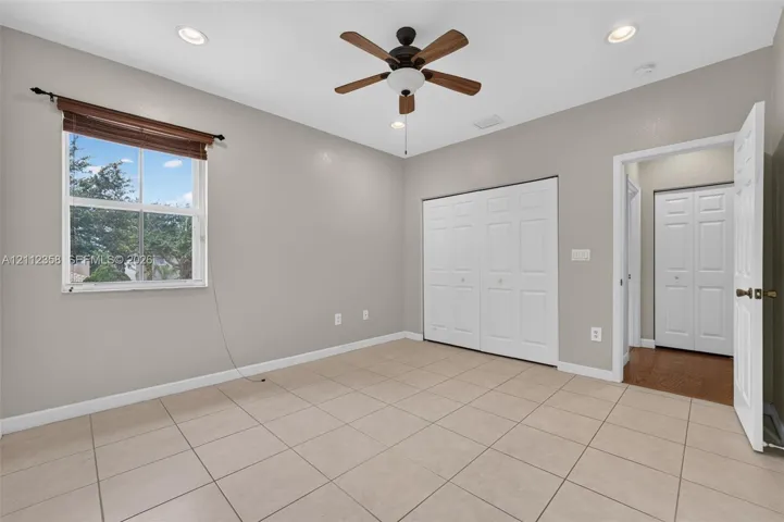 Room featuring tile flooring, neutral wall paint, recessed lighting, a ceiling fan with integrated light fixture, and double-panel closet doors