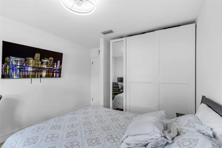 Built-in white shaker-style wardrobe featuring a full-length mirrored panel and a ceiling-mounted circular light fixture