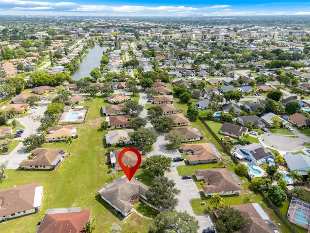 Aerial perspective featuring mature trees, expansive green space, and proximity to a community lake