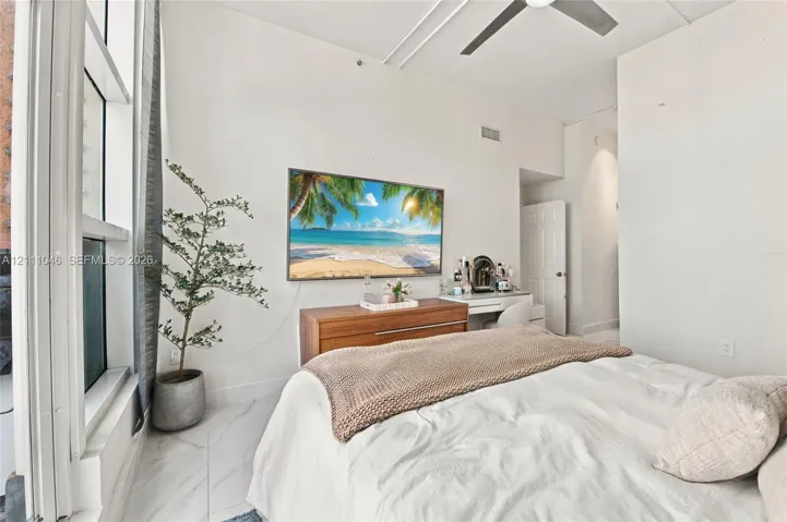 High ceilings featuring a modern ceiling fan, floor-to-ceiling windows, and polished stone-finish flooring