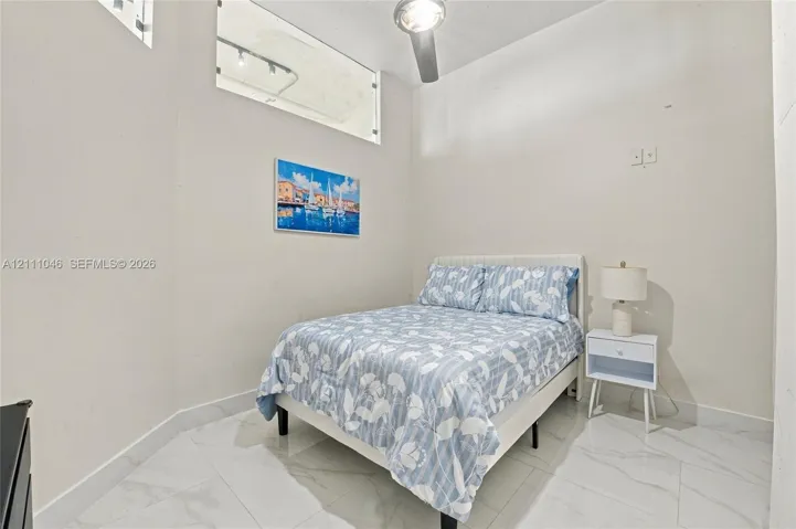 High-ceiling room featuring large-format tile flooring, transom window, and a modern ceiling-mounted light fixture