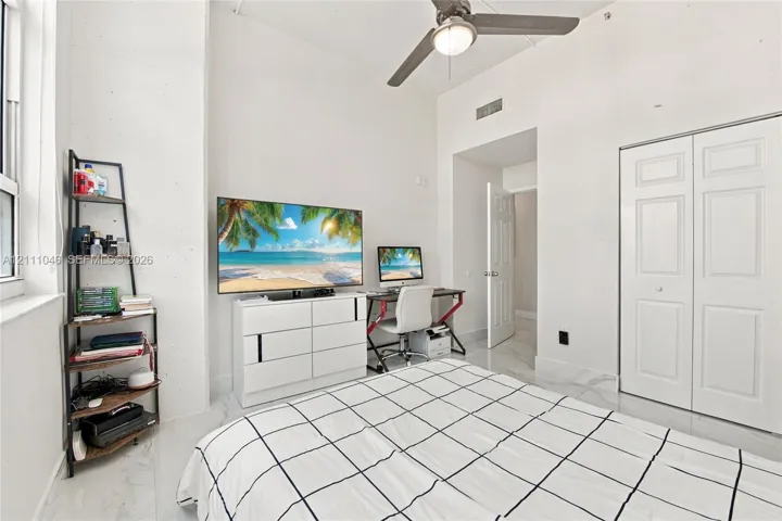 Room with high ceilings, stone-finish flooring, ceiling fan with integrated lighting, and a double-door closet