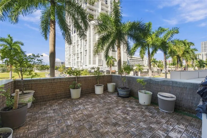 Private outdoor balcony featuring modular wood-tile decking and a textured masonry perimeter wall
