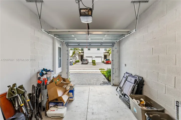 Single-car garage featuring concrete block walls, a concrete floor, and an overhead door motor