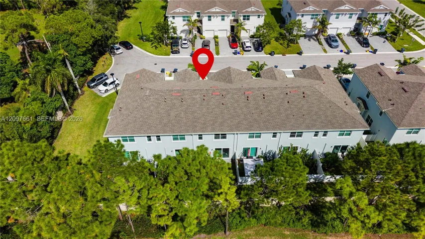 Multi-story residence featuring a shingled roof, light-toned exterior finish, and fenced rear outdoor area with mature perimeter landscaping