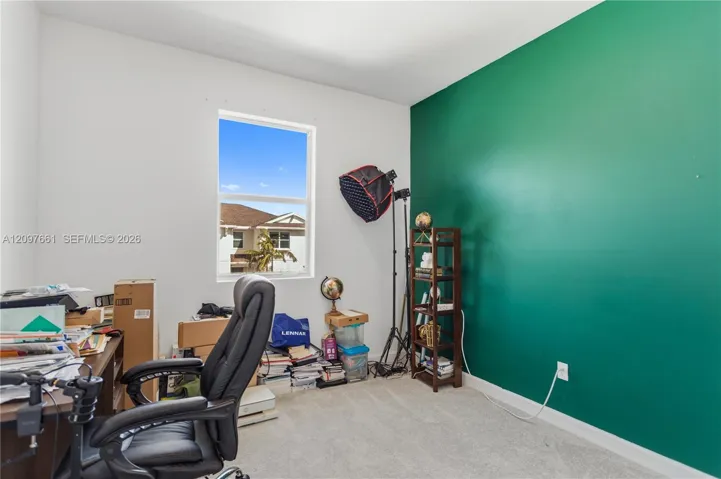Room featuring a vibrant green accent wall, neutral carpeting, and a large window providing natural light