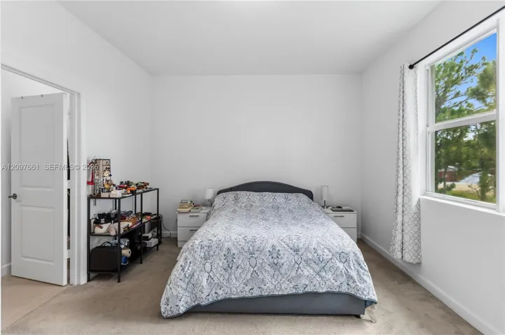 Interior room featuring wall-to-wall carpeting, neutral interior paint, and a single-hung window with exterior scenery