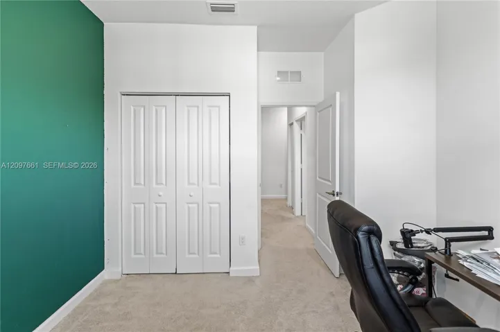 Neutral-toned carpeting, white bi-fold closet doors, and a contrasting feature wall