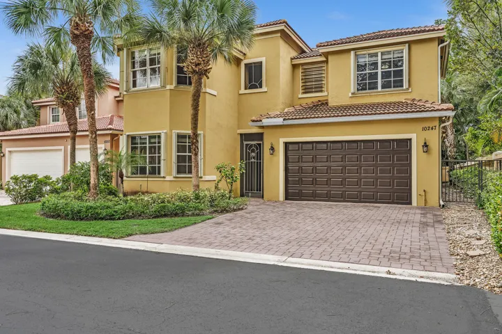 Two-story residence featuring a stucco exterior, clay tile roof, paver driveway, multi-pane windows, and attached two-car garage